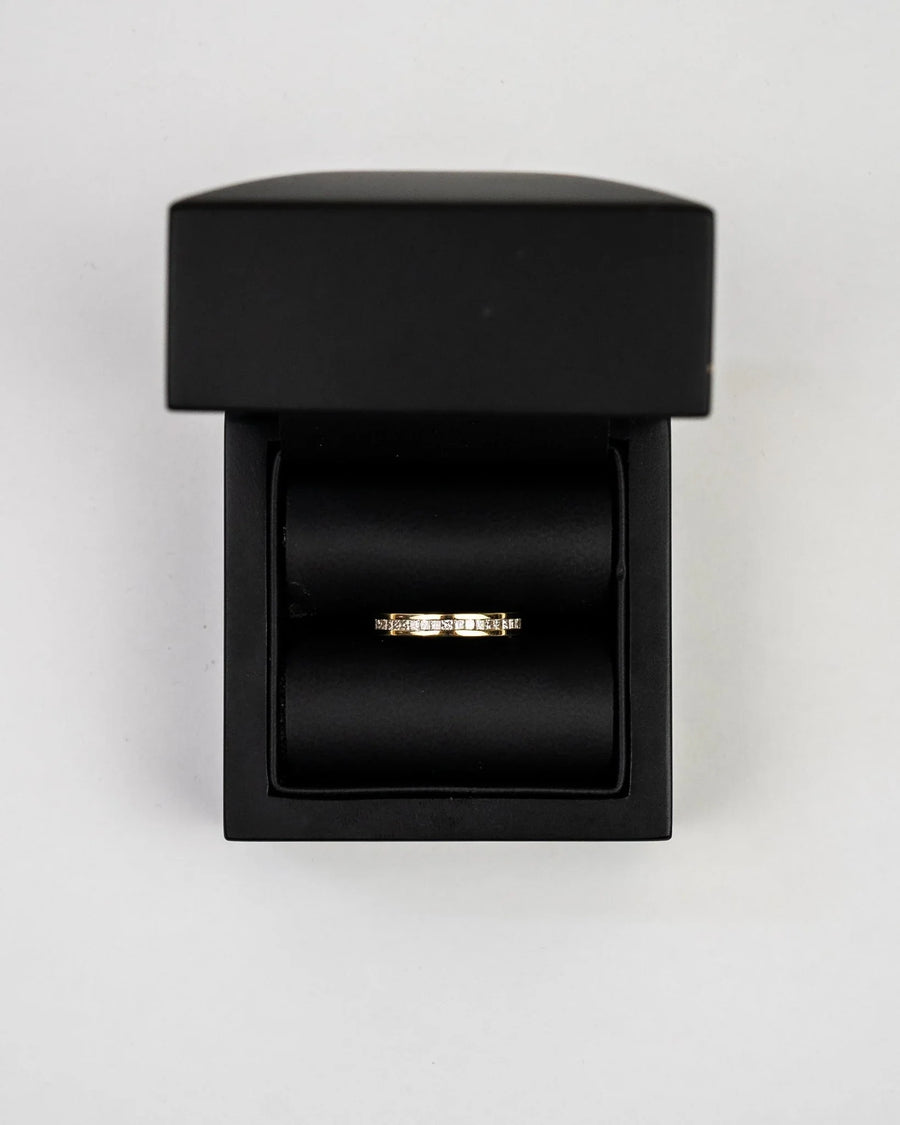 Gold channel set diamond hinged ring in a black box.