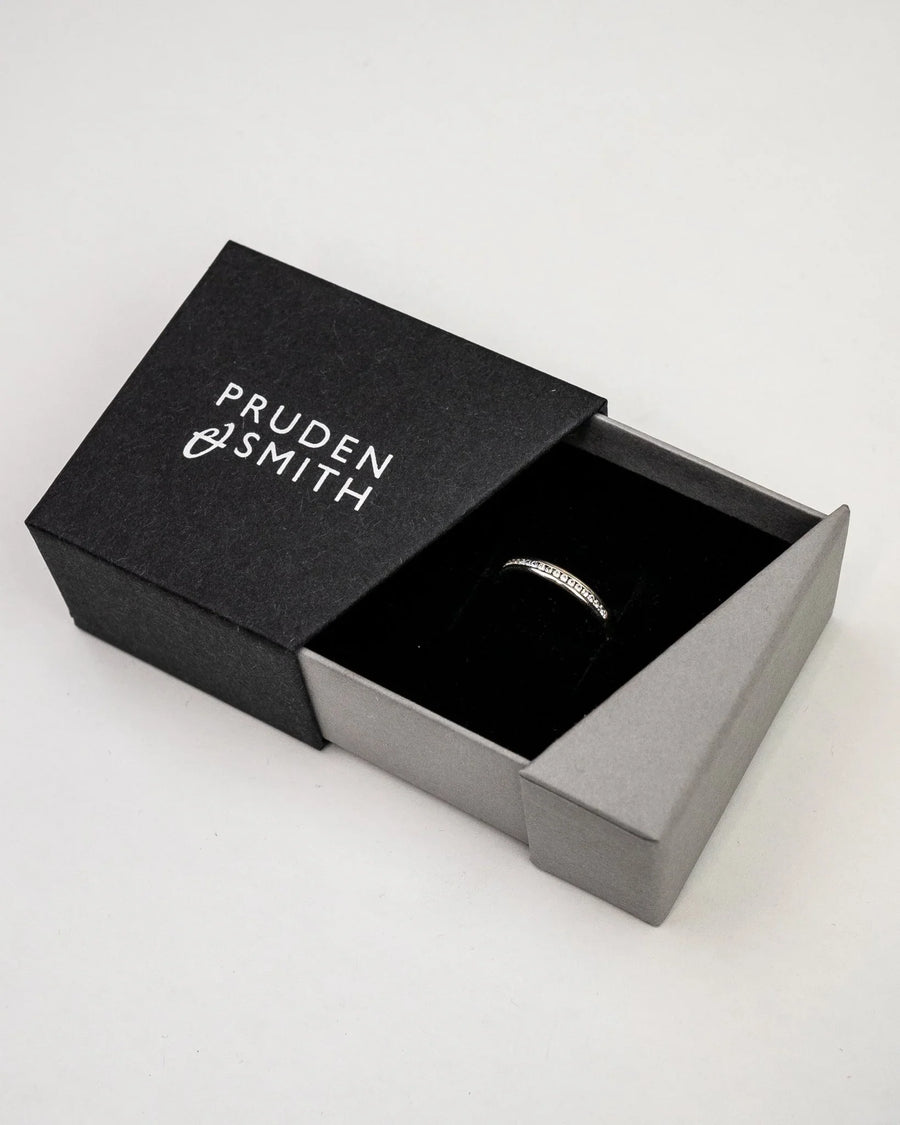 Silver channel set diamond ring in a black and gray box.