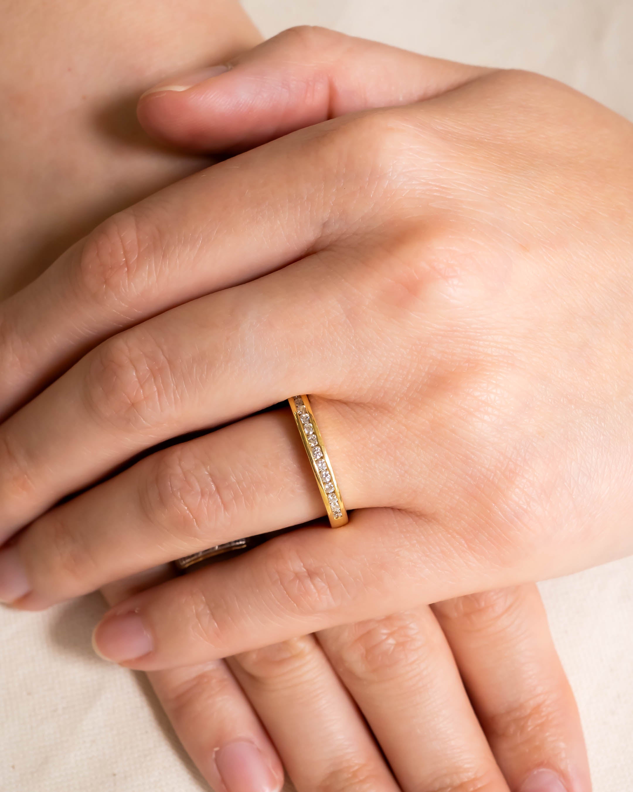 Gold channel set round brilliant diamond ring on a hand.