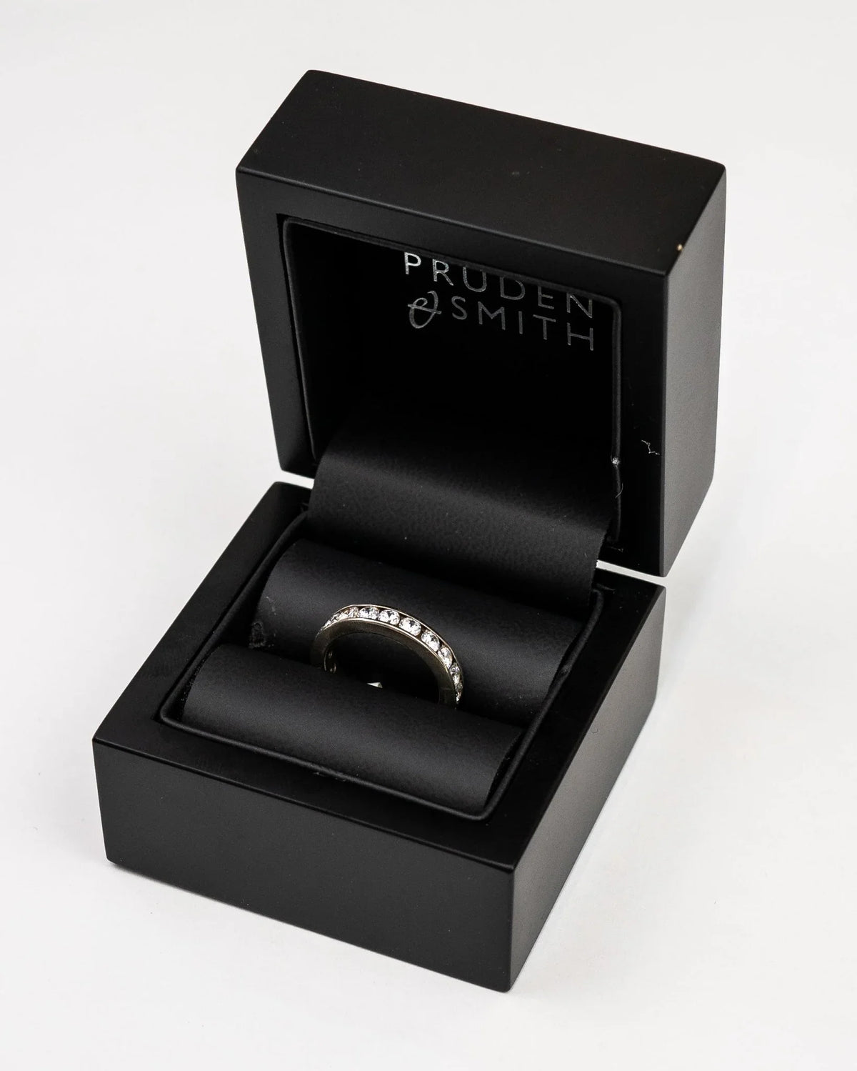 Silver channel set round brilliant diamond ring in a black box.