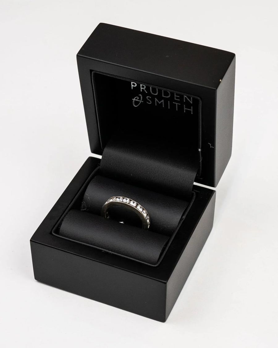 Silver channel set round brilliant diamond ring in a black box.