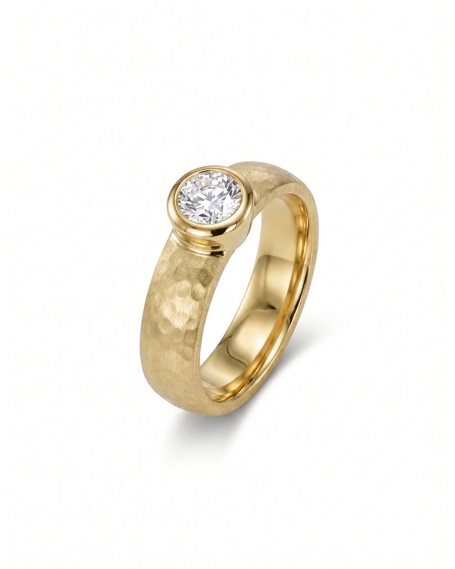 Gold engagement ring with a chunky bezel brilliant cut diamond.
