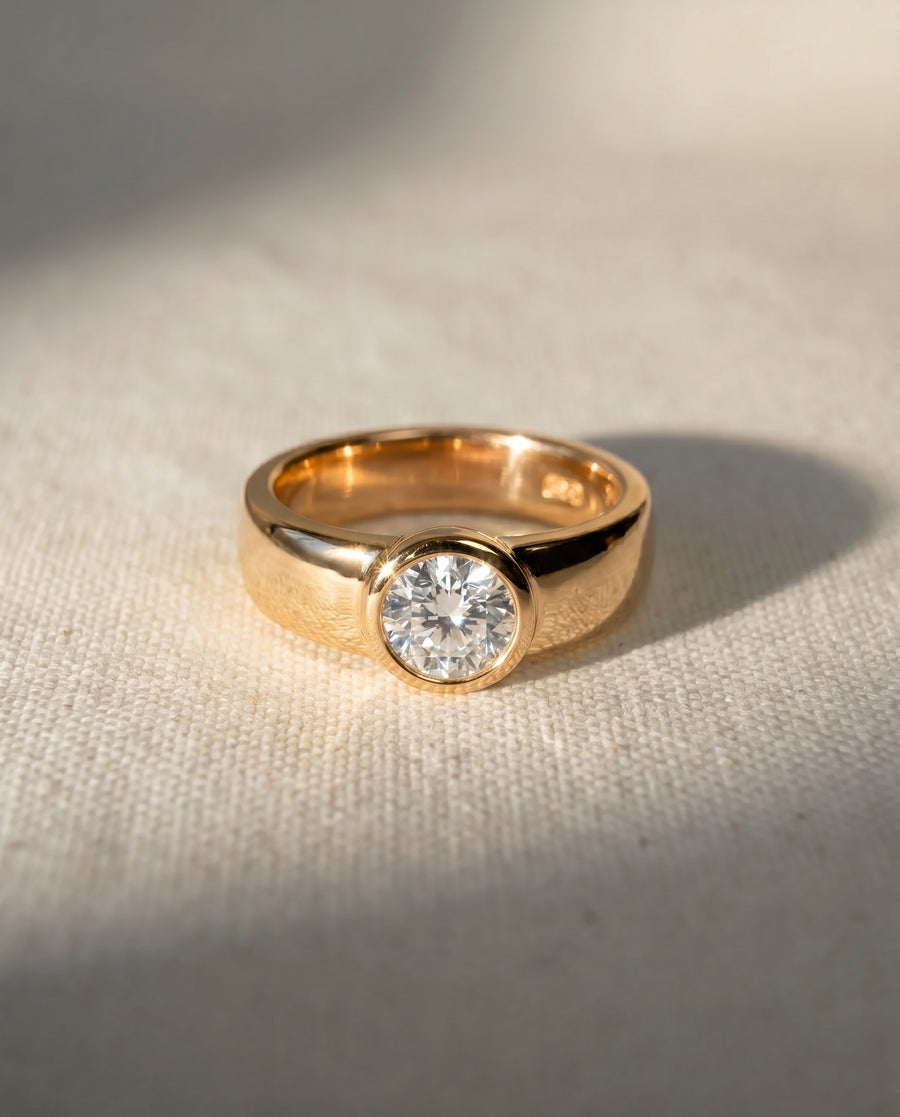 Gold chunky bezel solitaire engagement ring with a brilliant cut diamond.