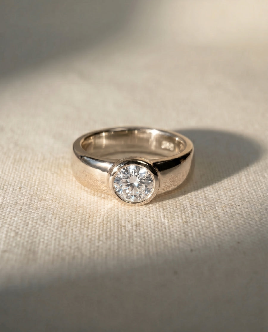 Yellow gold chunky bezel solitaire engagement ring with a brilliant cut diamond.