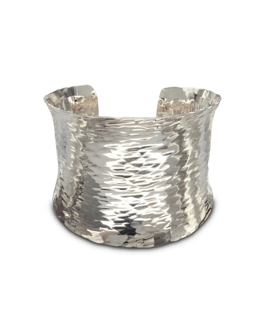 Wide hammered silver cuff bracelet with organic, textured finish on white background
