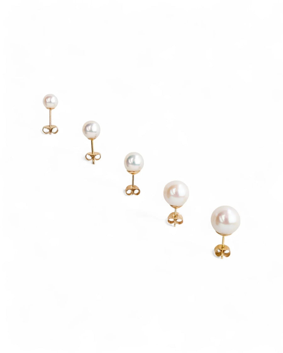 Five 9ct yellow gold round pearl stud earrings in varying sizes.
