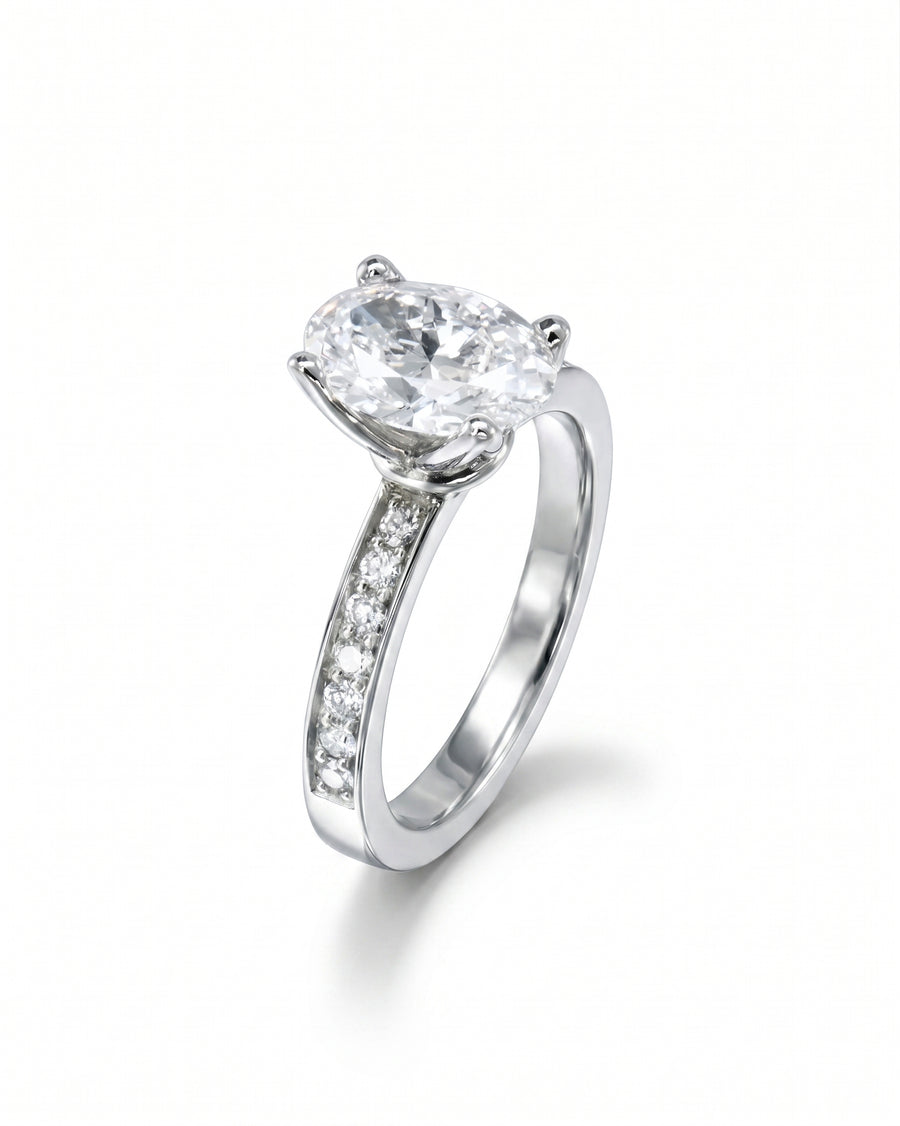 Silver claw oval diamond engagement ring with pavé set diamond band.