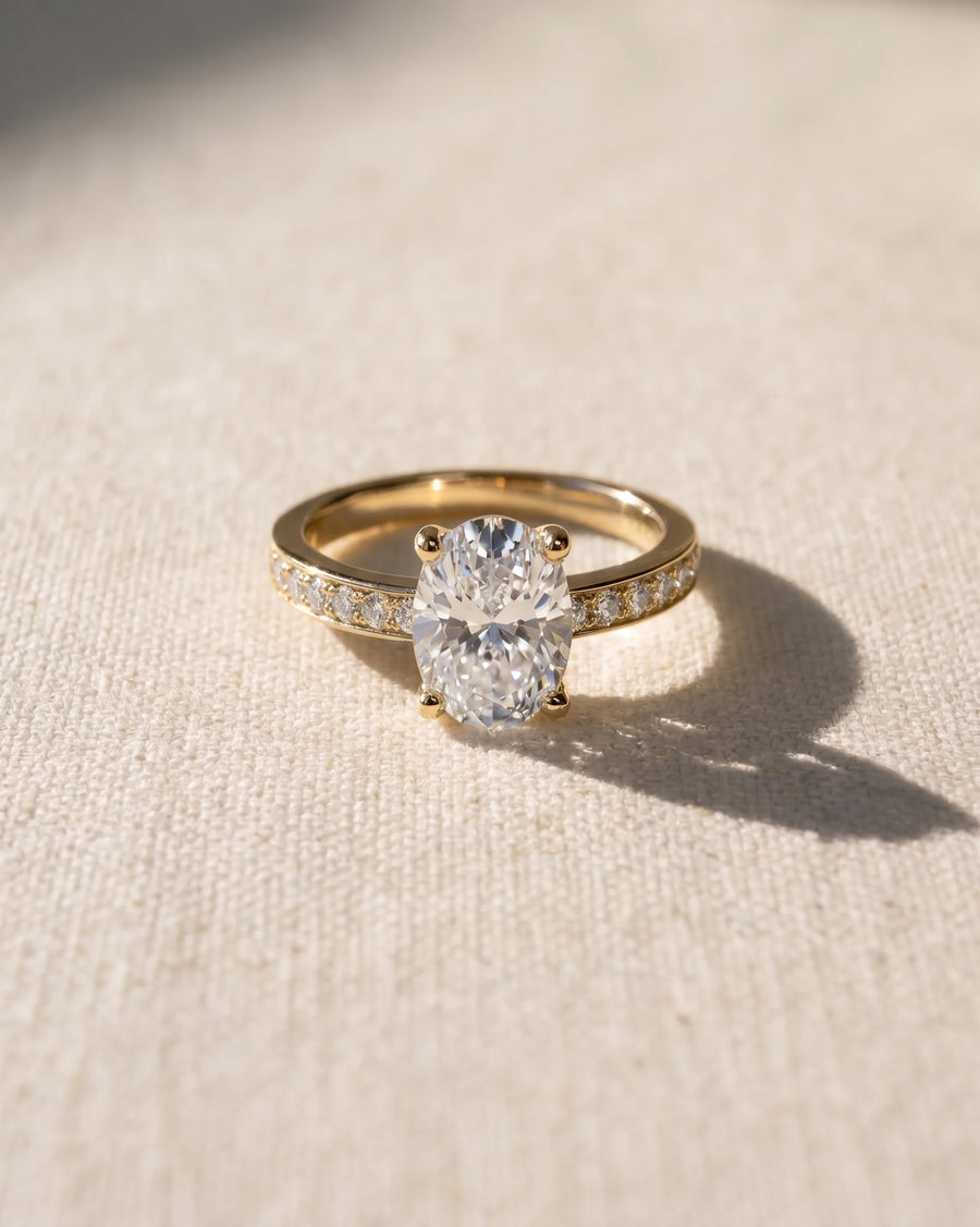 18ct yellow gold oval diamond engagement ring with pavé set diamond band.