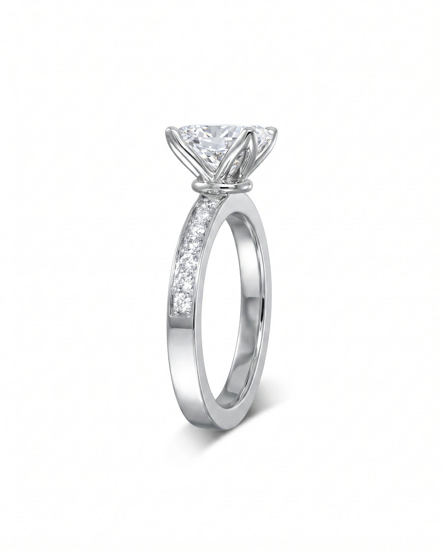 Silver claw oval diamond engagement ring with a pavé set diamond band.