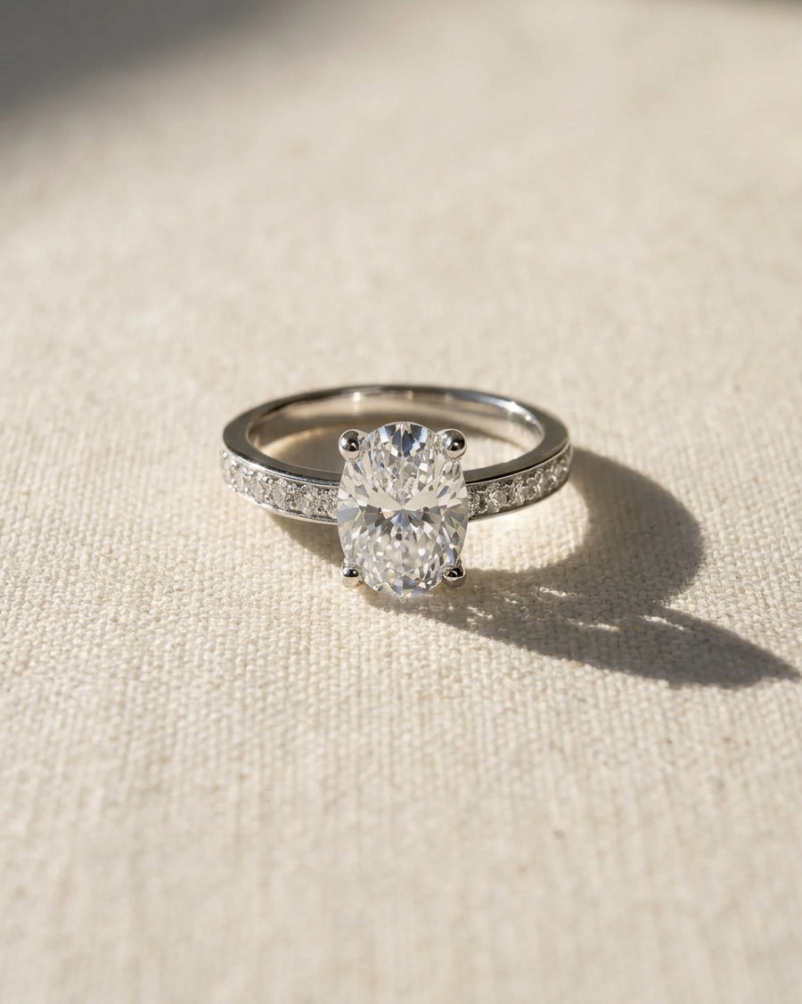 Platinum engagement ring with an oval diamond and pavé set diamond band.