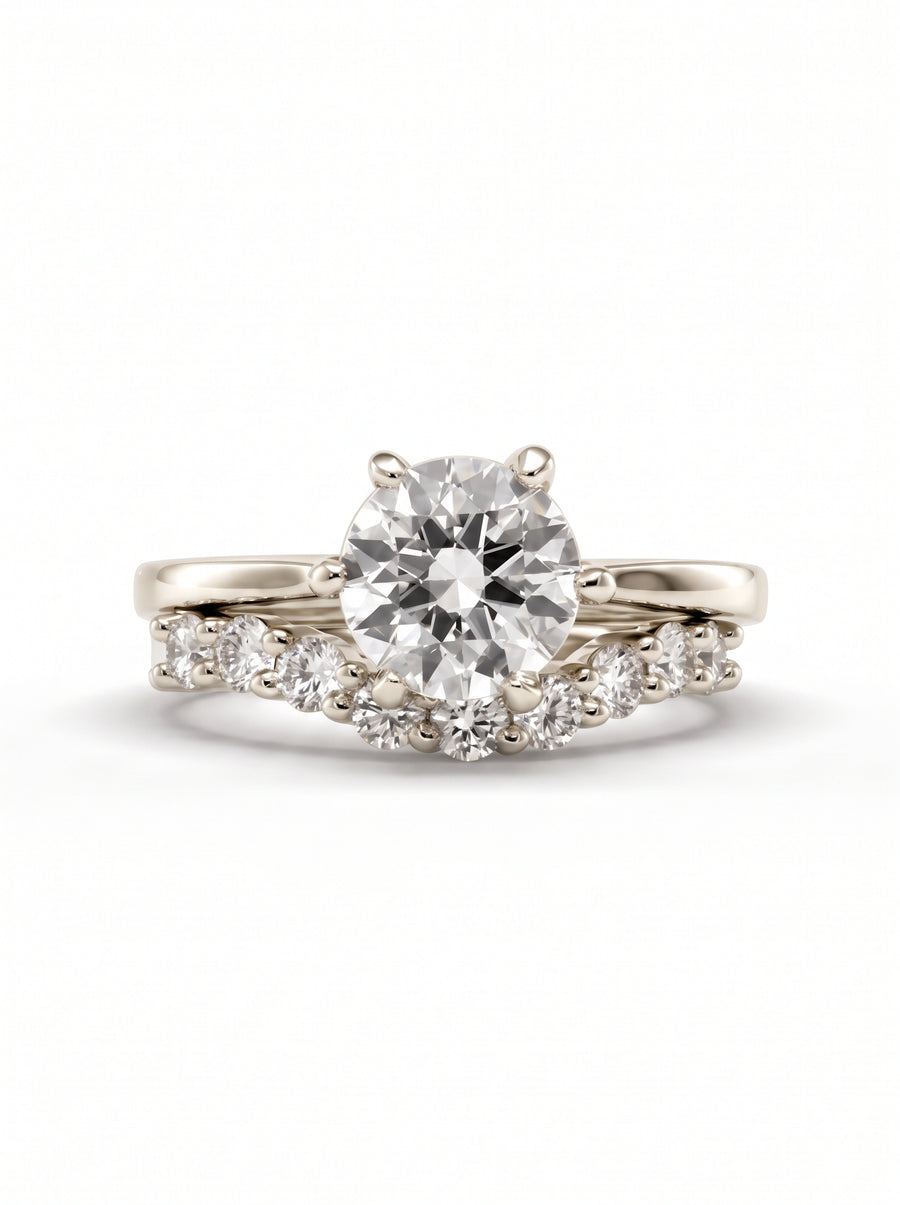 Round cut diamond solitaire engagement ring with a curved diamond-studded wedding band in polished white gold.