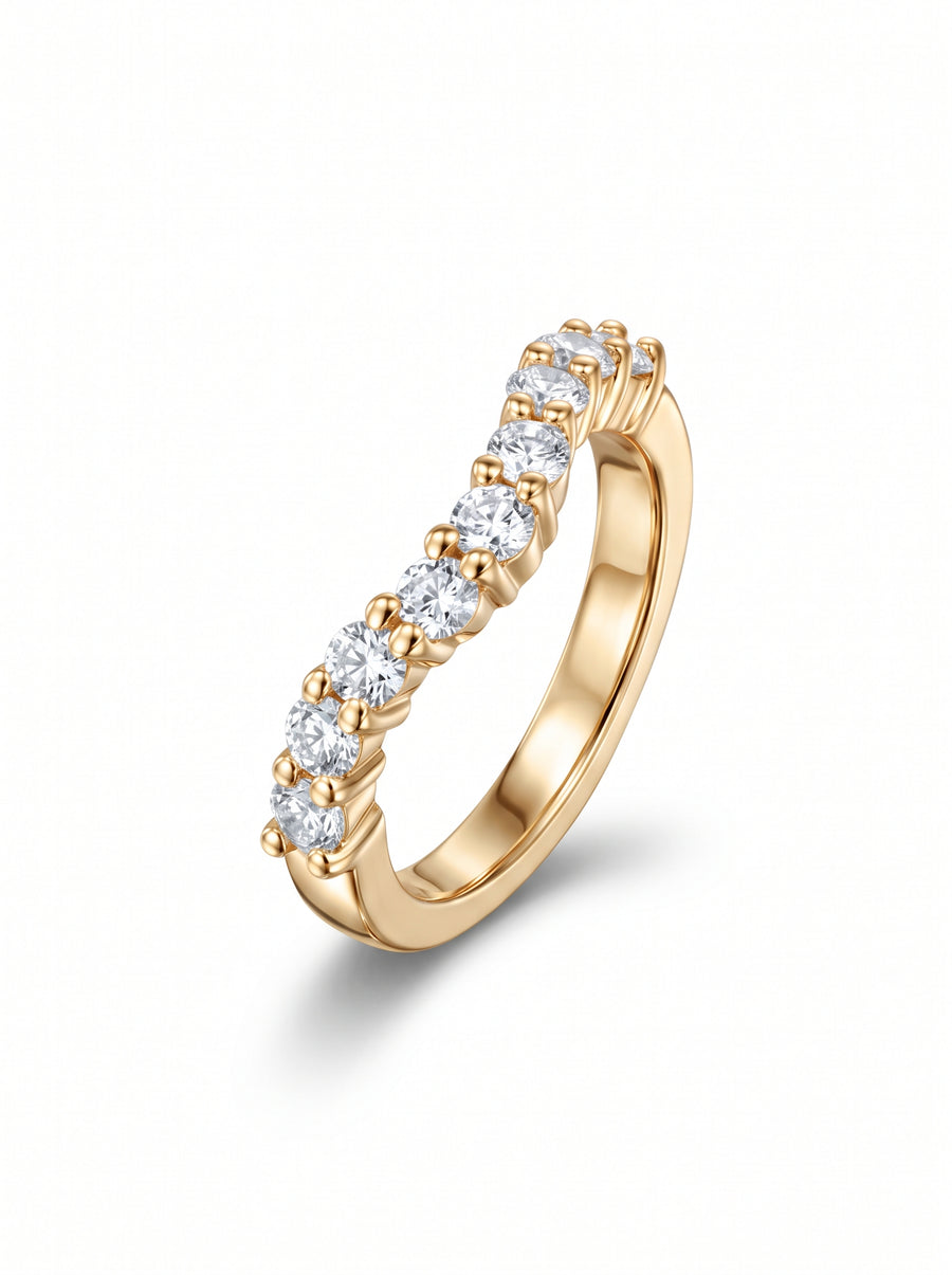 Gold wedding ring featuring a curved band set with round cut diamonds in claw settings.