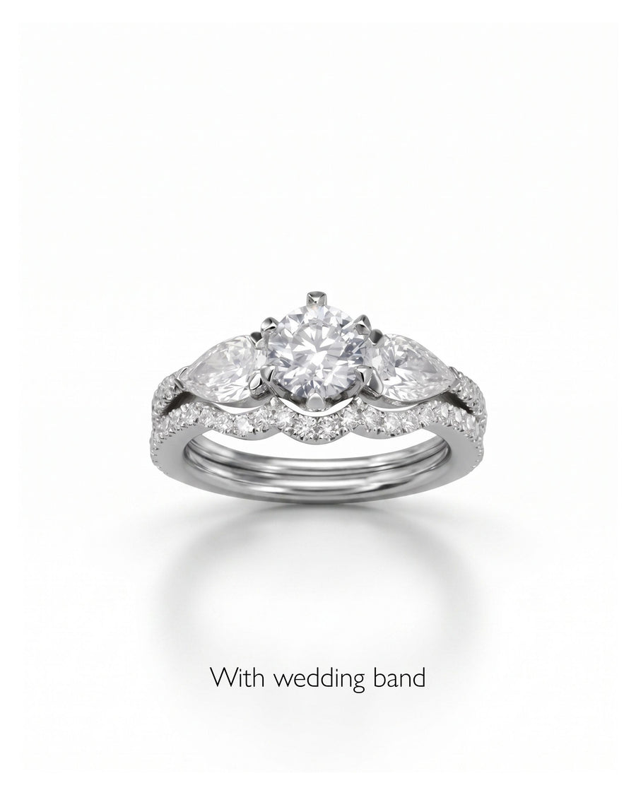 Silver claw round and pear cut diamond trilogy engagement ring with wedding band.