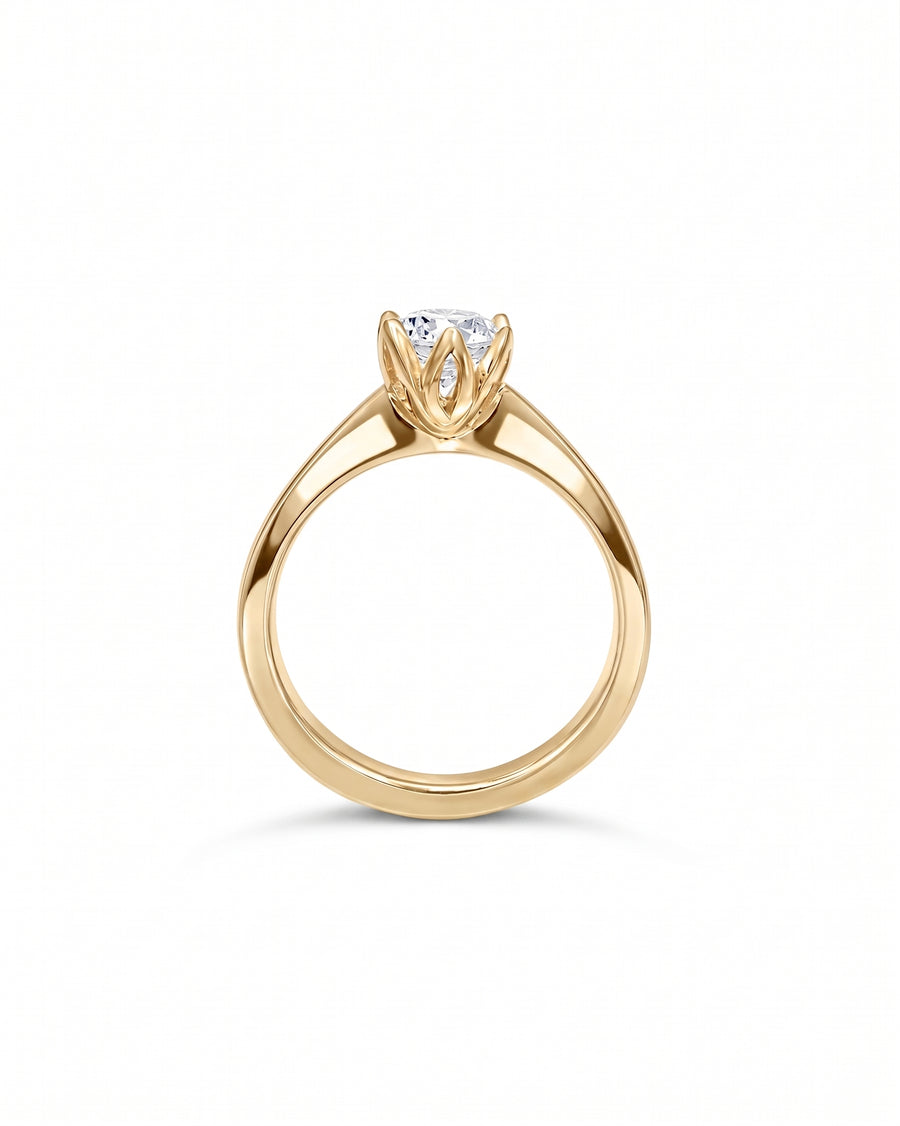 Gold engagement ring with a round brilliant diamond in a tulip-style claw setting.