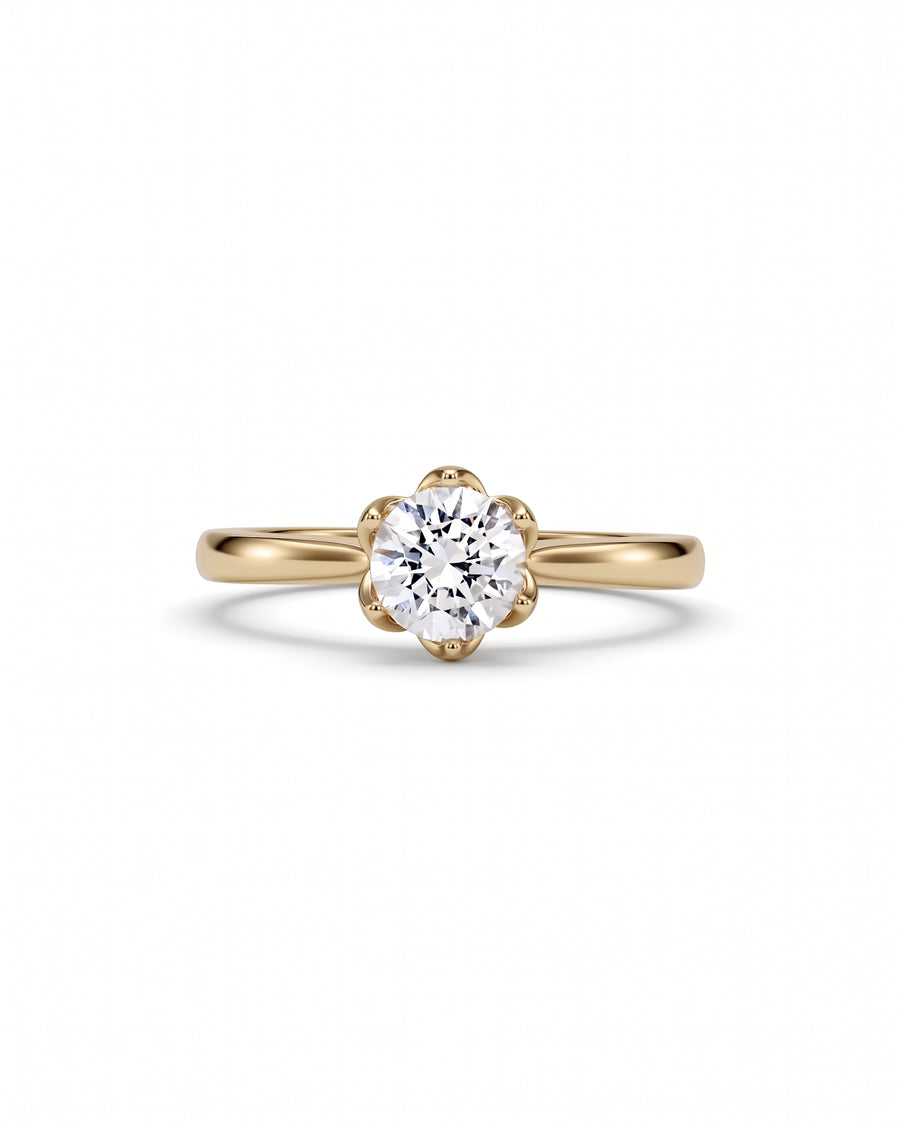 Round brilliant cut diamond engagement ring in a yellow gold claw setting on a white background.
