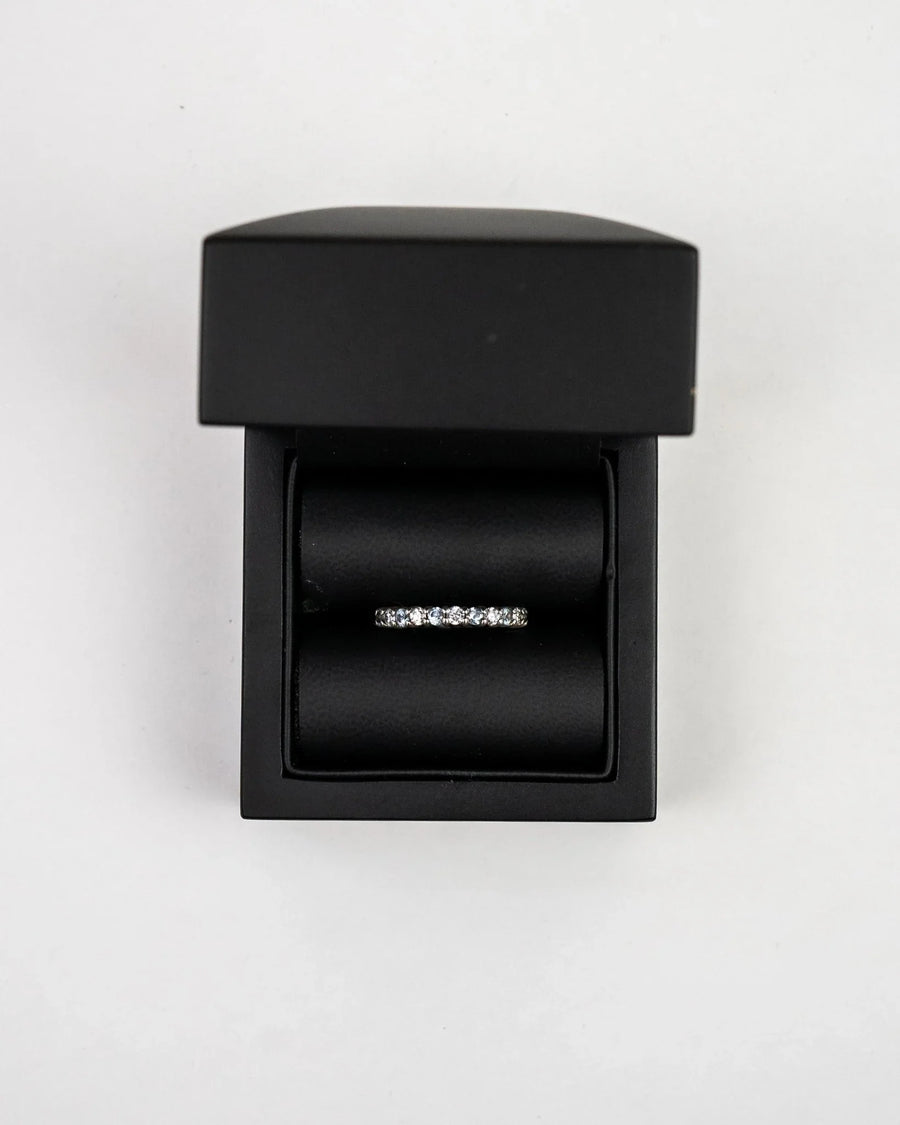Silver claw set diamond half eternity ring in a black box.
