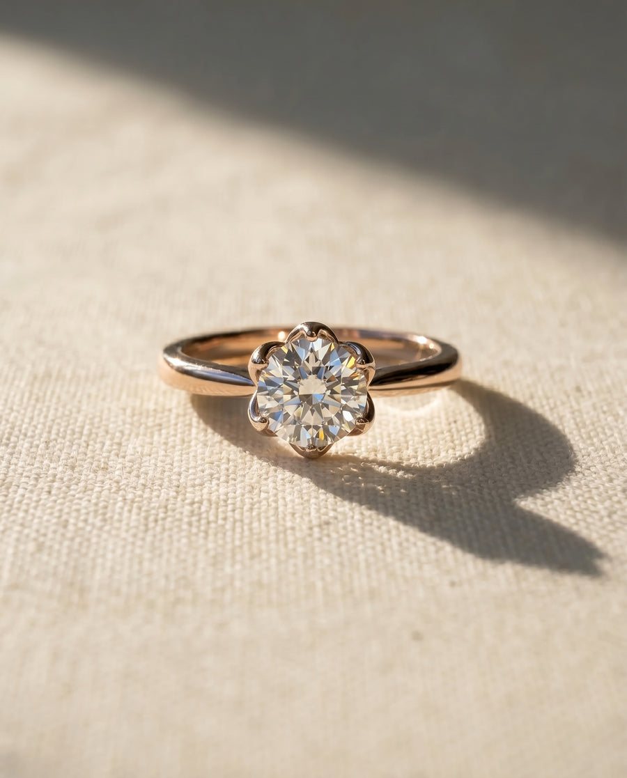 Rose gold engagement ring with a round diamond in a floral claw setting.