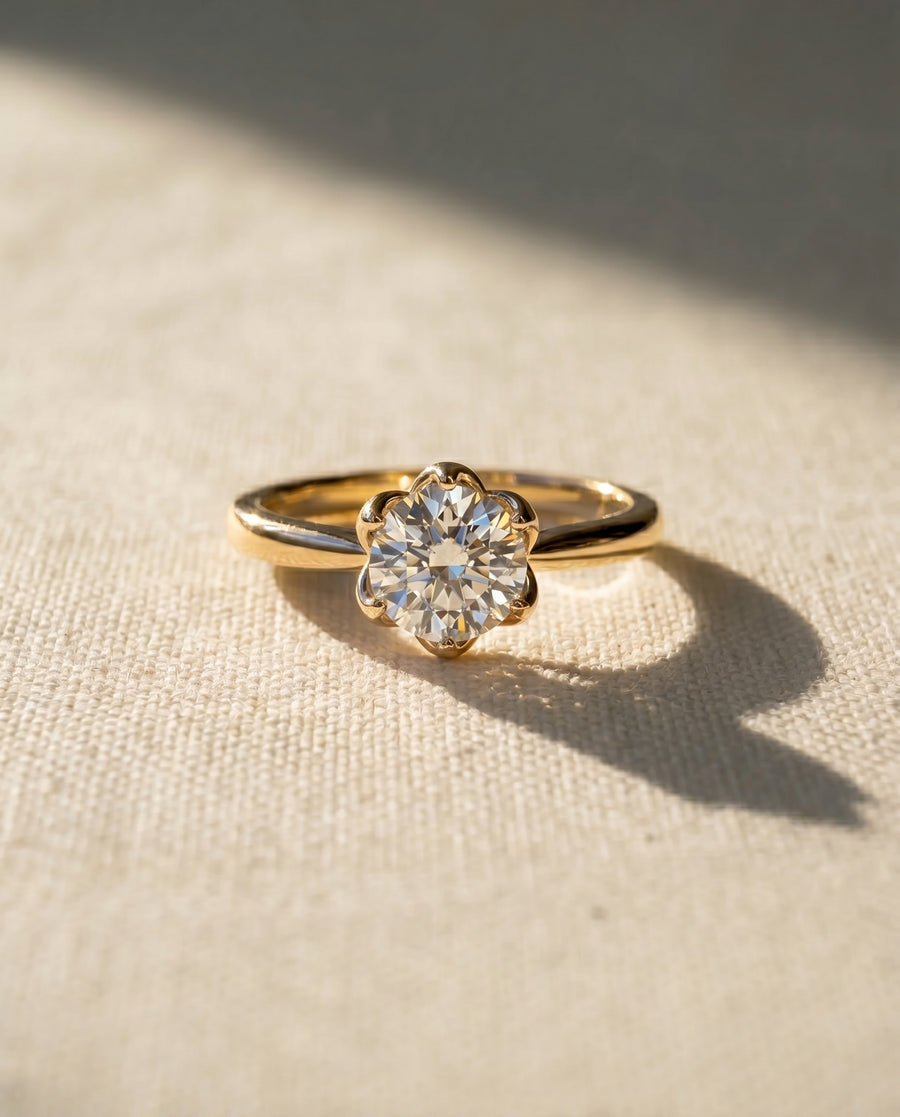 Yellow gold engagement ring with a round diamond in a six-claw floral setting.