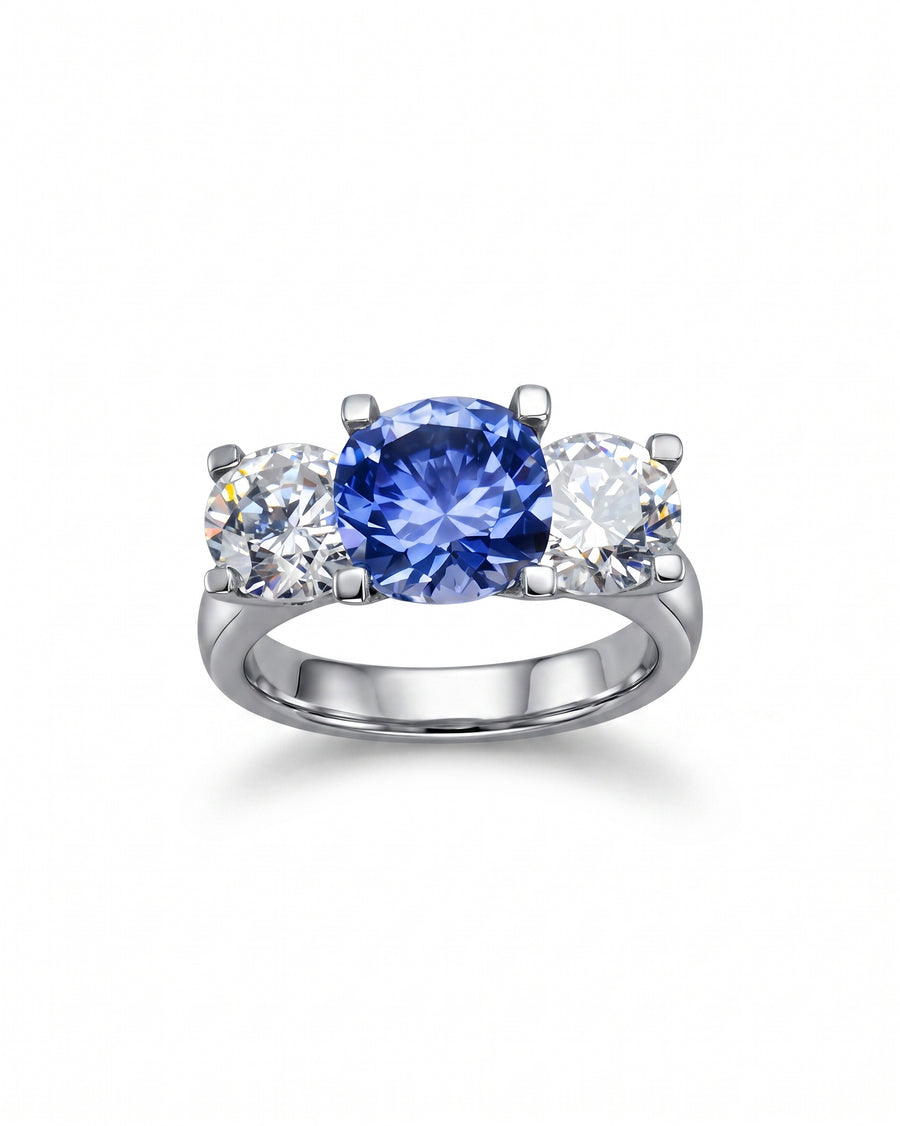 Platinum trilogy ring with a claw set blue sapphire and two round diamonds.