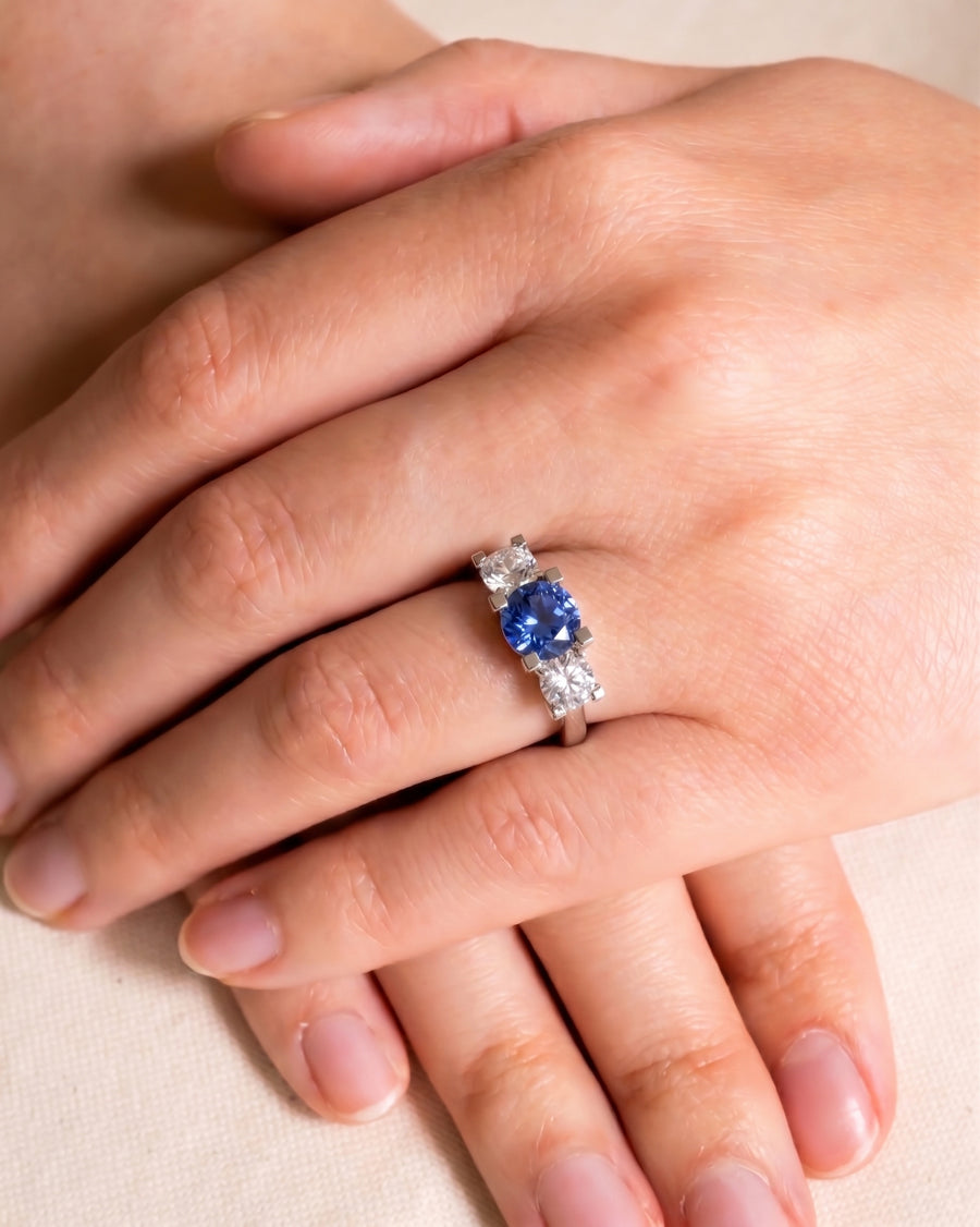 Platinum trilogy ring with a claw set blue sapphire and two diamonds.