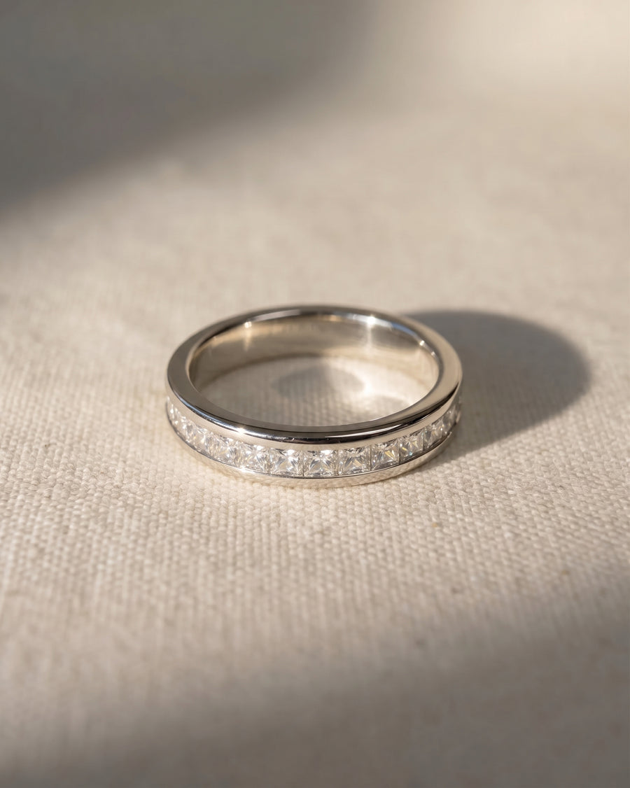 Platinum ring with a band of princess cut diamonds.