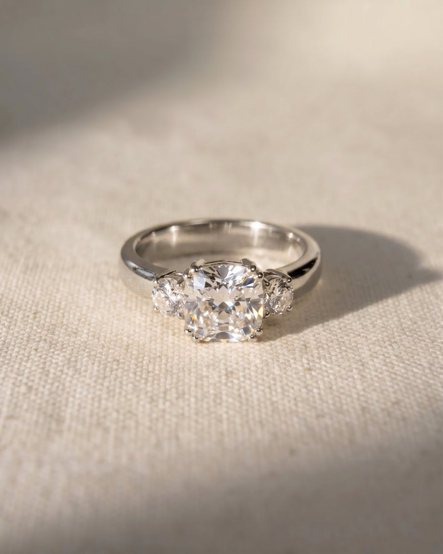 Platinum cushion cut trilogy engagement ring with lab-grown diamonds.