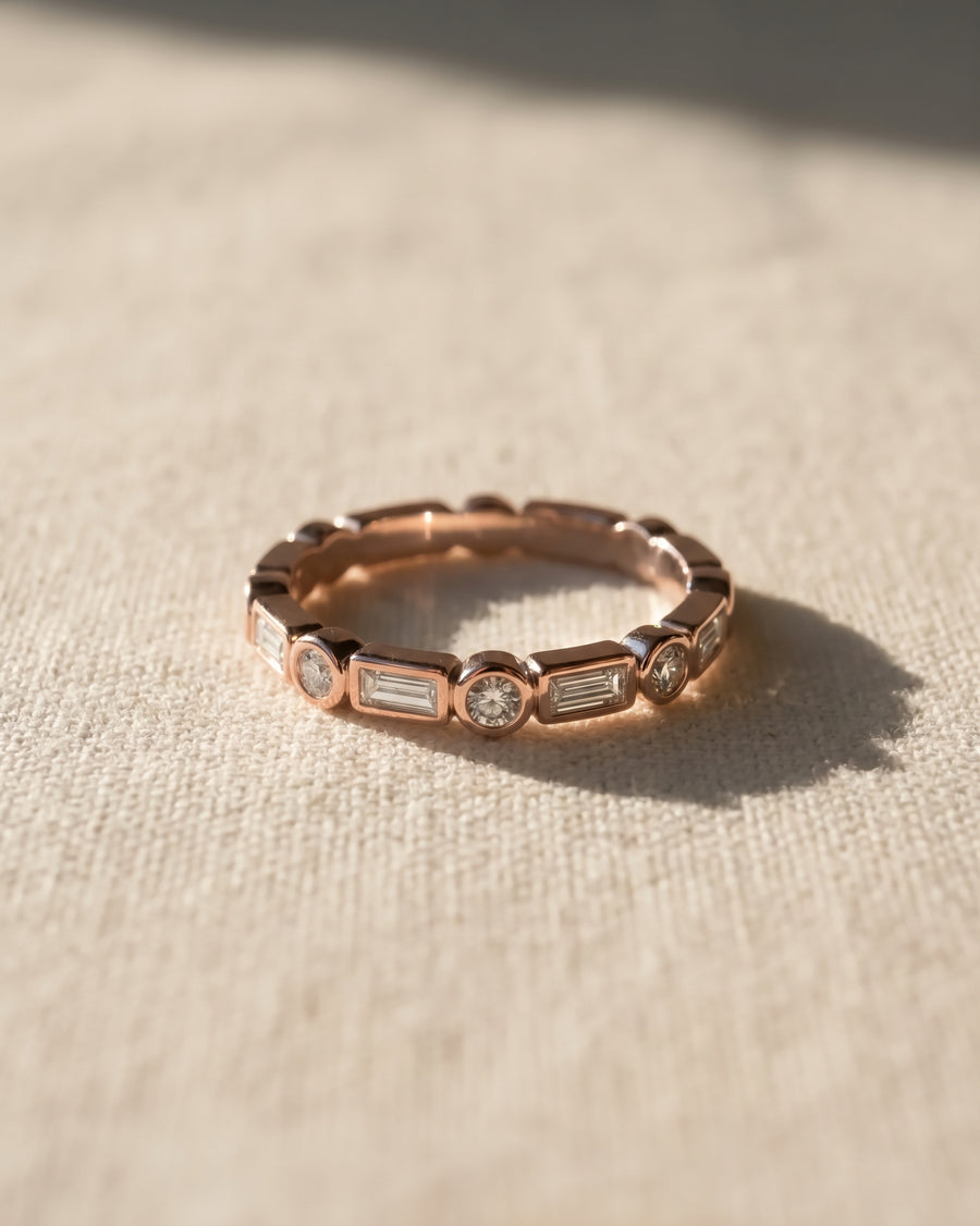 9ct rose gold eternity ring featuring alternating baguette and round diamonds in a bezel setting.