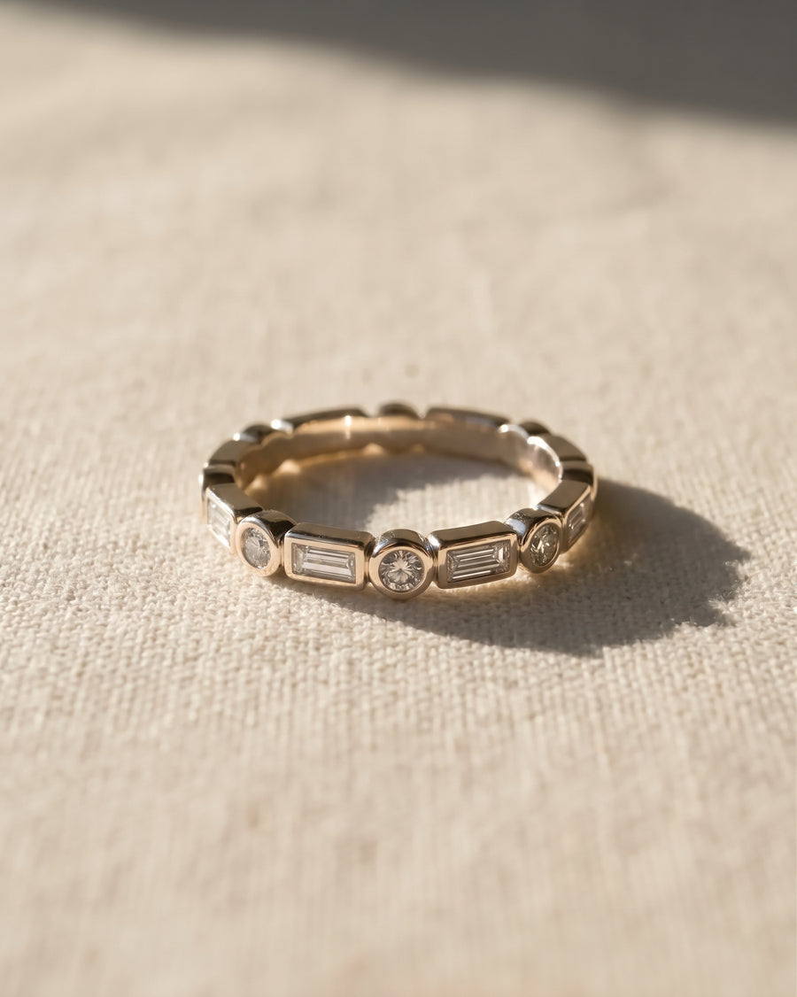 9ct white gold eternity ring featuring alternating baguette and round diamonds in a bezel setting.