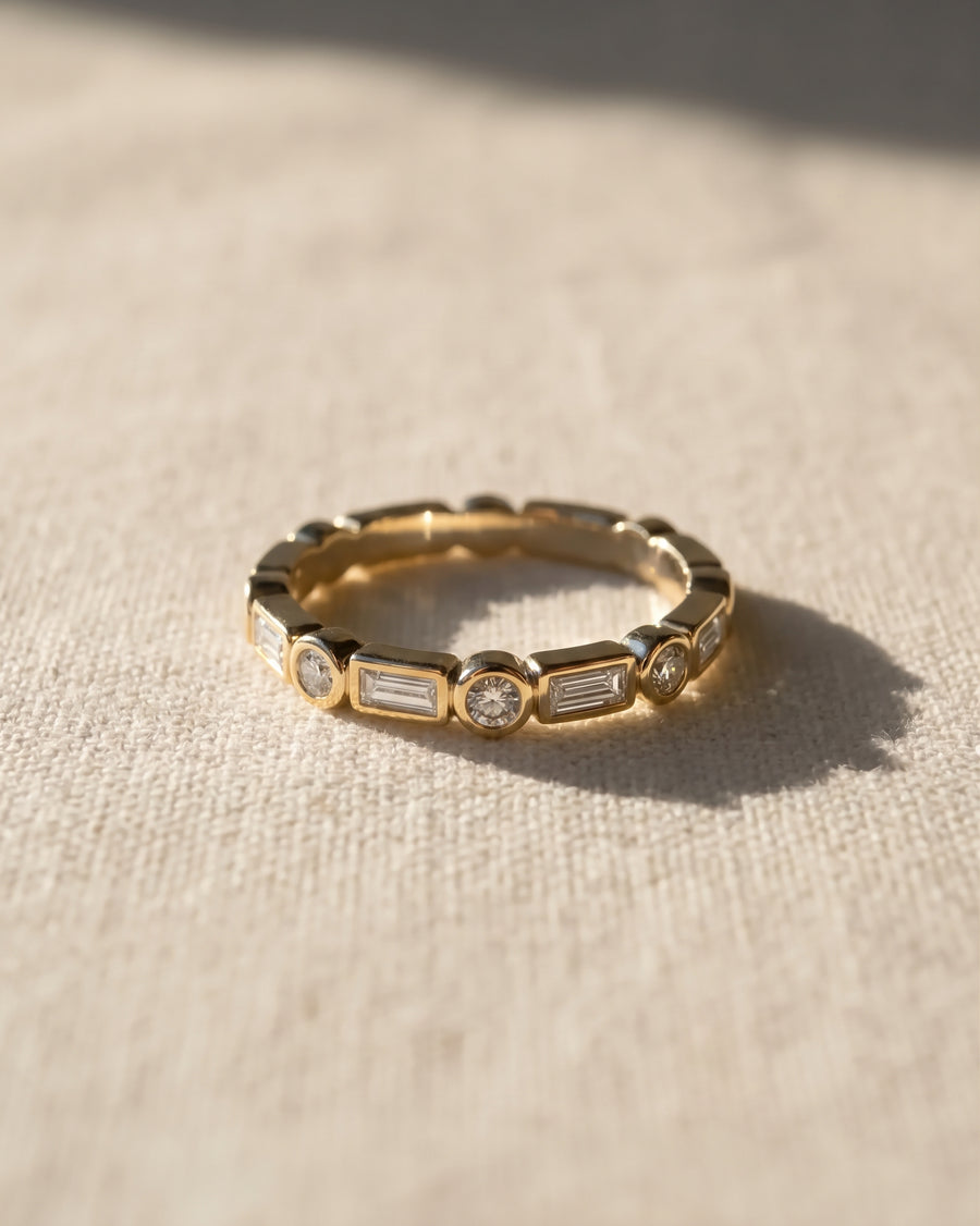 9ct yellow gold eternity ring featuring alternating baguette and round diamonds in a bezel setting.