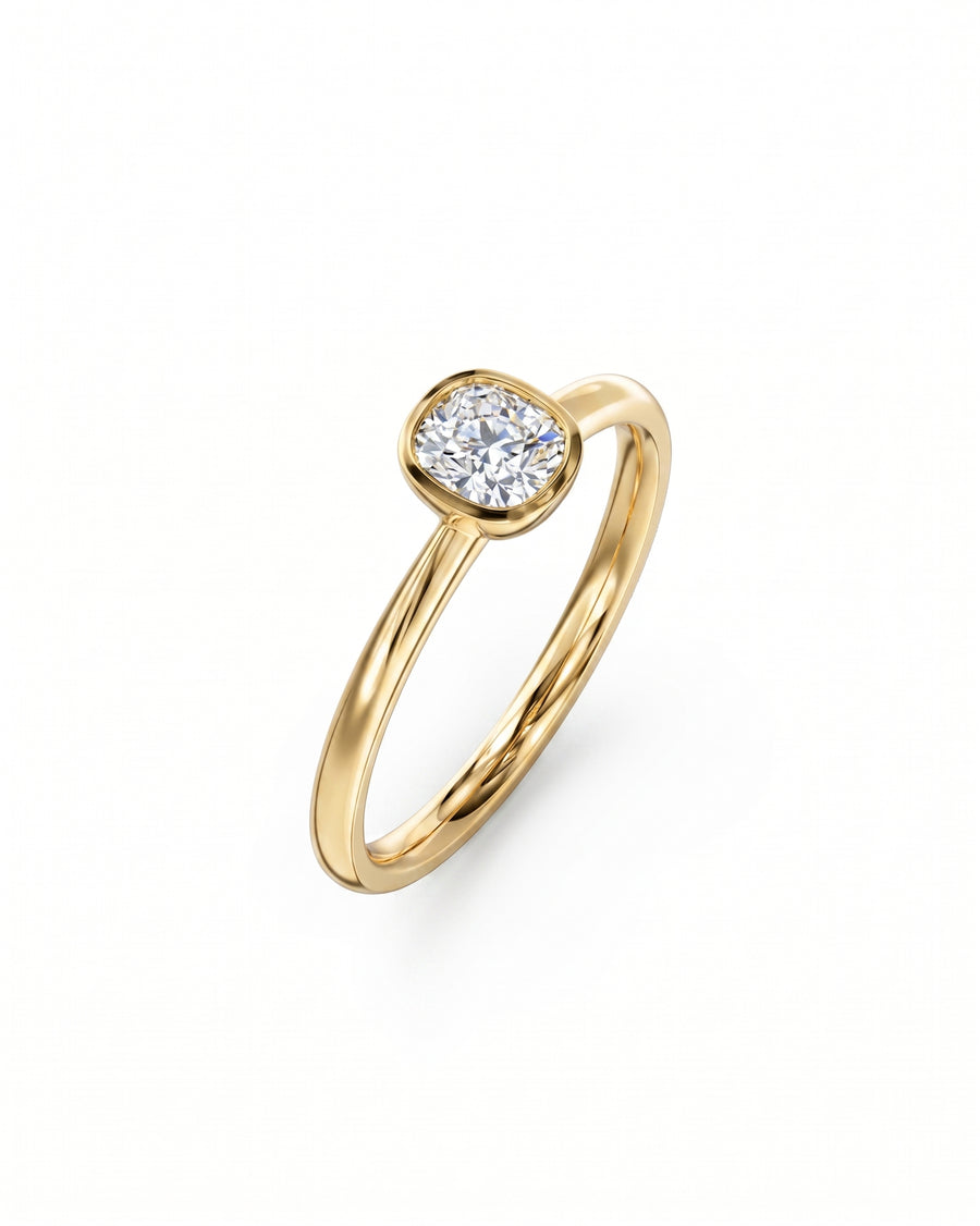 Gold engagement ring with a cushion cut diamond in a bezel setting.