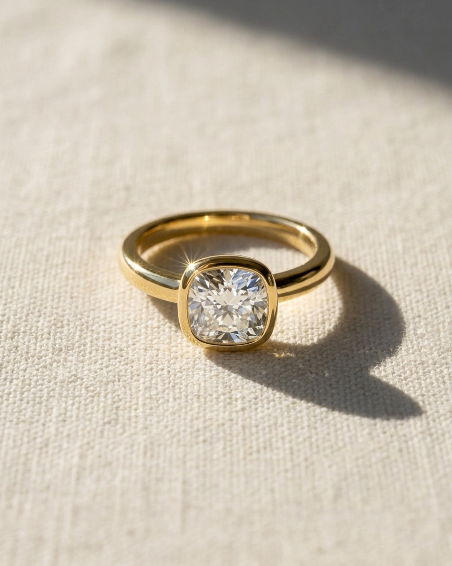 18ct yellow gold engagement ring with a 1ct lab grown cushion cut diamond in a bezel setting.