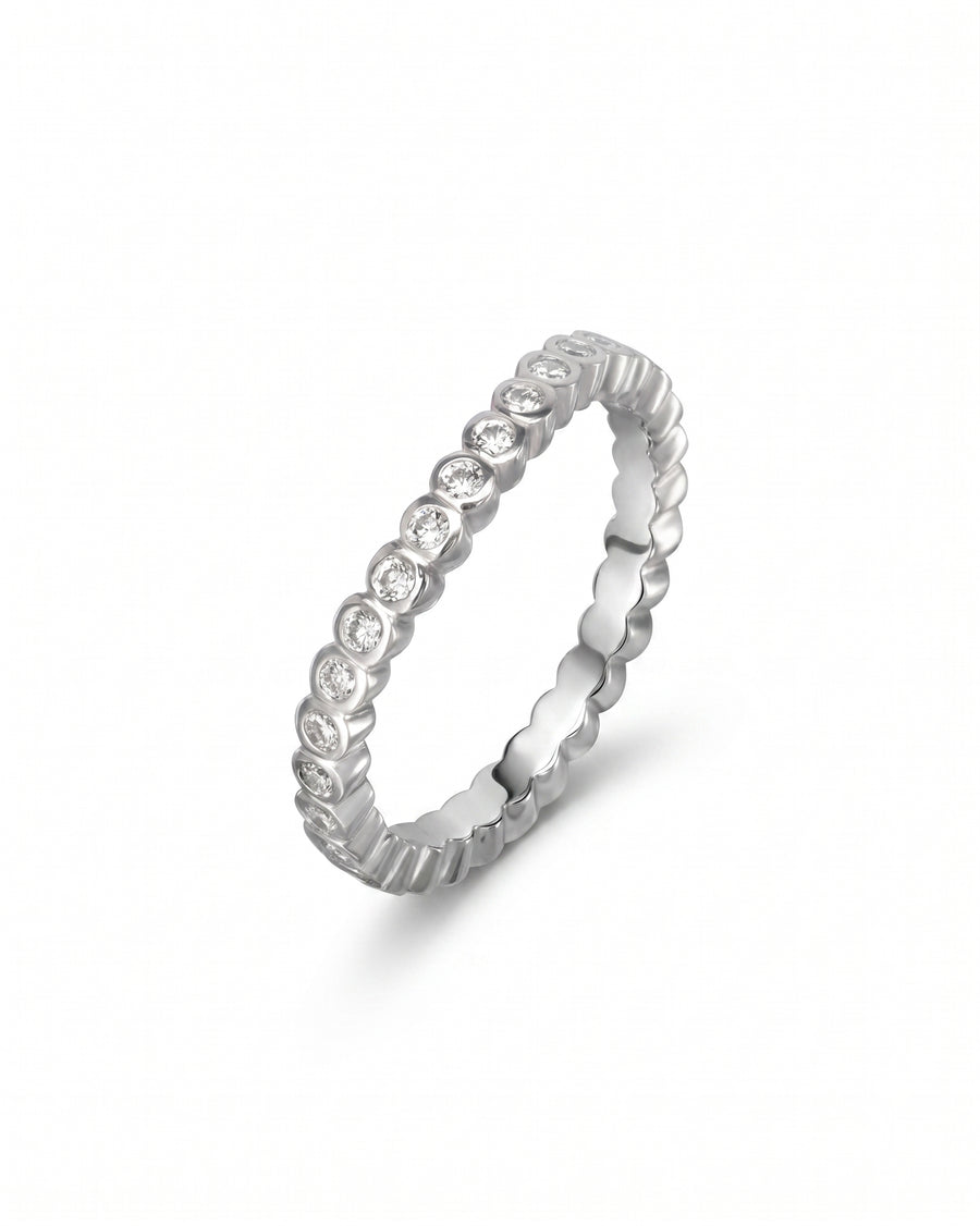 Silver wedding band with dainty round diamonds in a bezel setting.