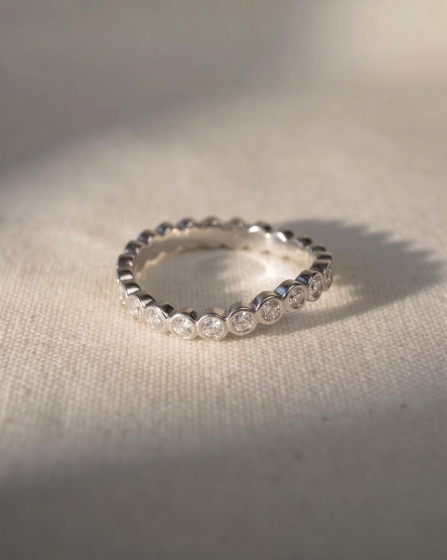 Silver wedding band with dainty round diamonds in a bezel setting.