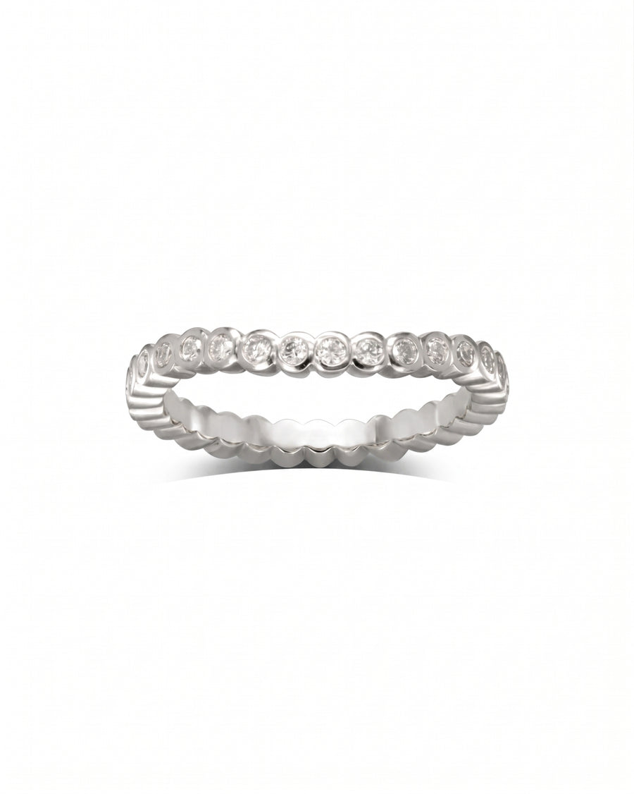 Platinum wedding band with dainty, bezel-set diamonds in a continuous circle.