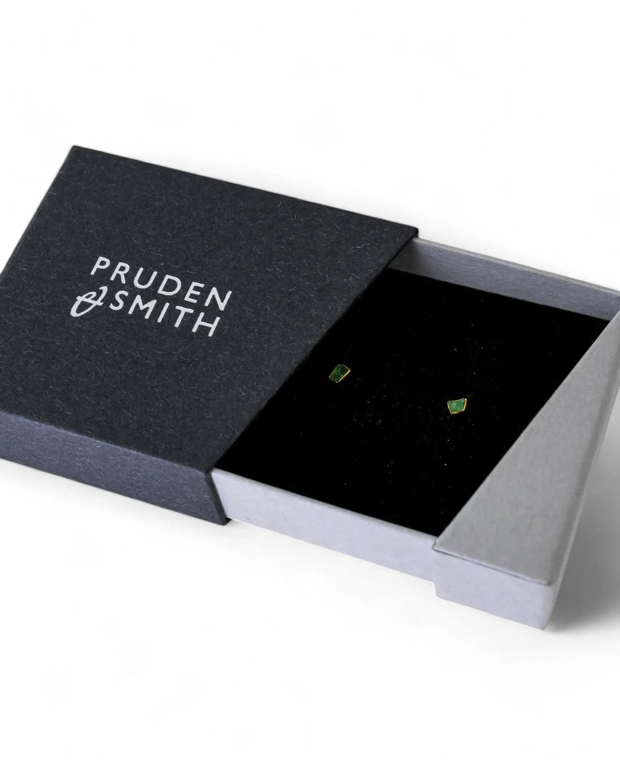 Dainty rough green gemstone 18ct gold stud earrings in a black box.