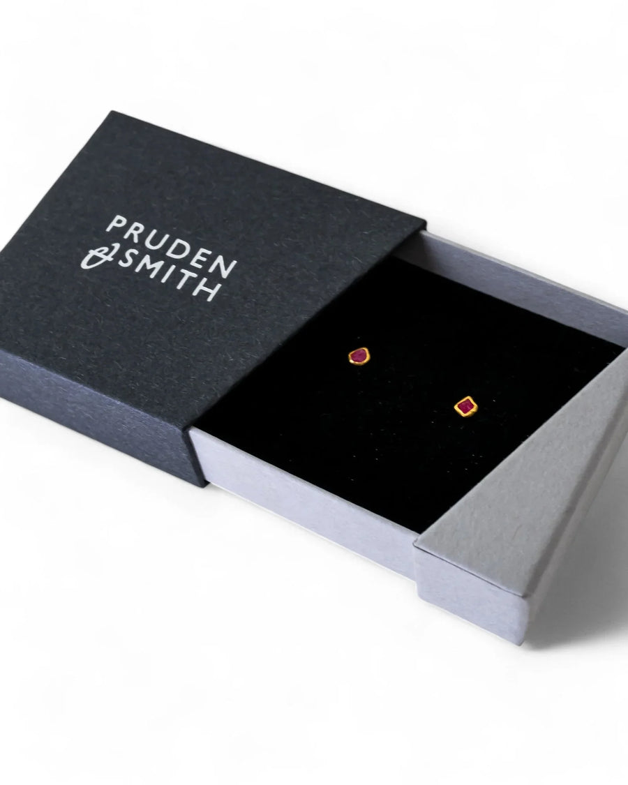 18ct gold stud earrings with dainty rough red gemstones in a black box.