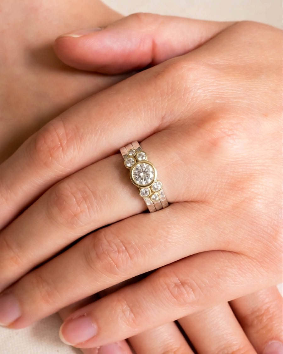 Dainty rough hammered diamond stacking ring set on a hand.