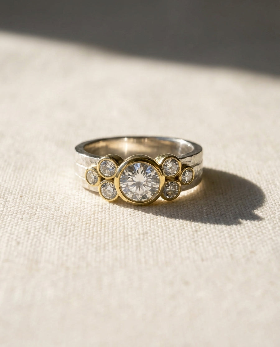 9ct white and yellow gold ring with a central diamond and smaller surrounding diamonds.