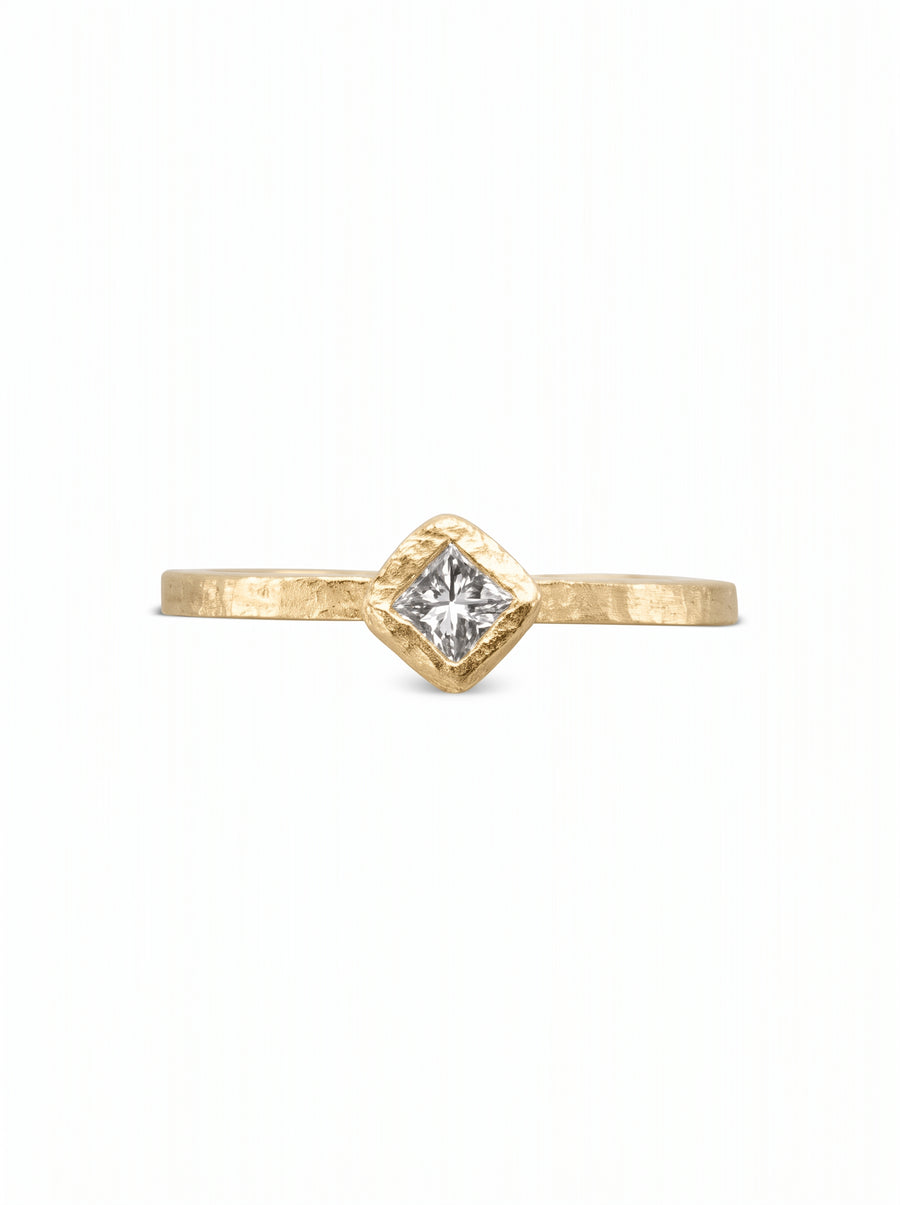 Gold engagement ring with a hammered texture and a square princess-cut diamond in a bezel setting.