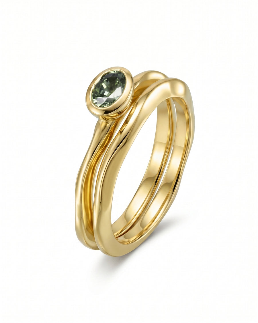 Gold engagement ring with a bezel-set green sapphire.