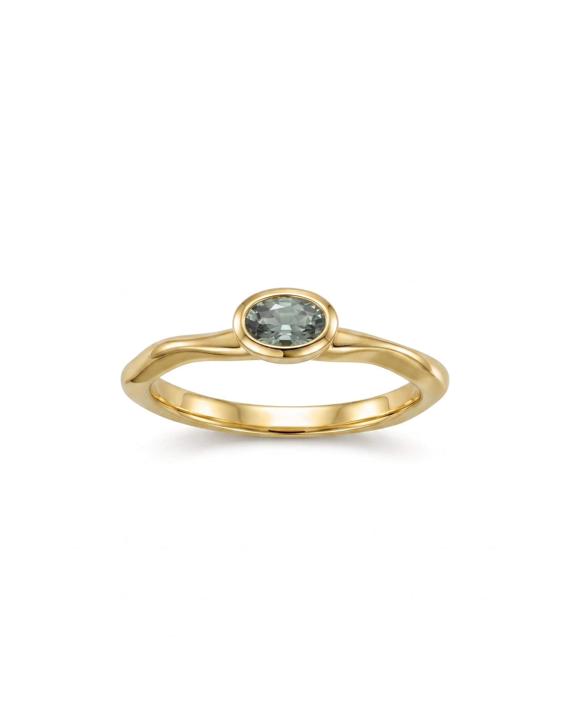 Gold ring with an oval blue sapphire in a bezel setting.