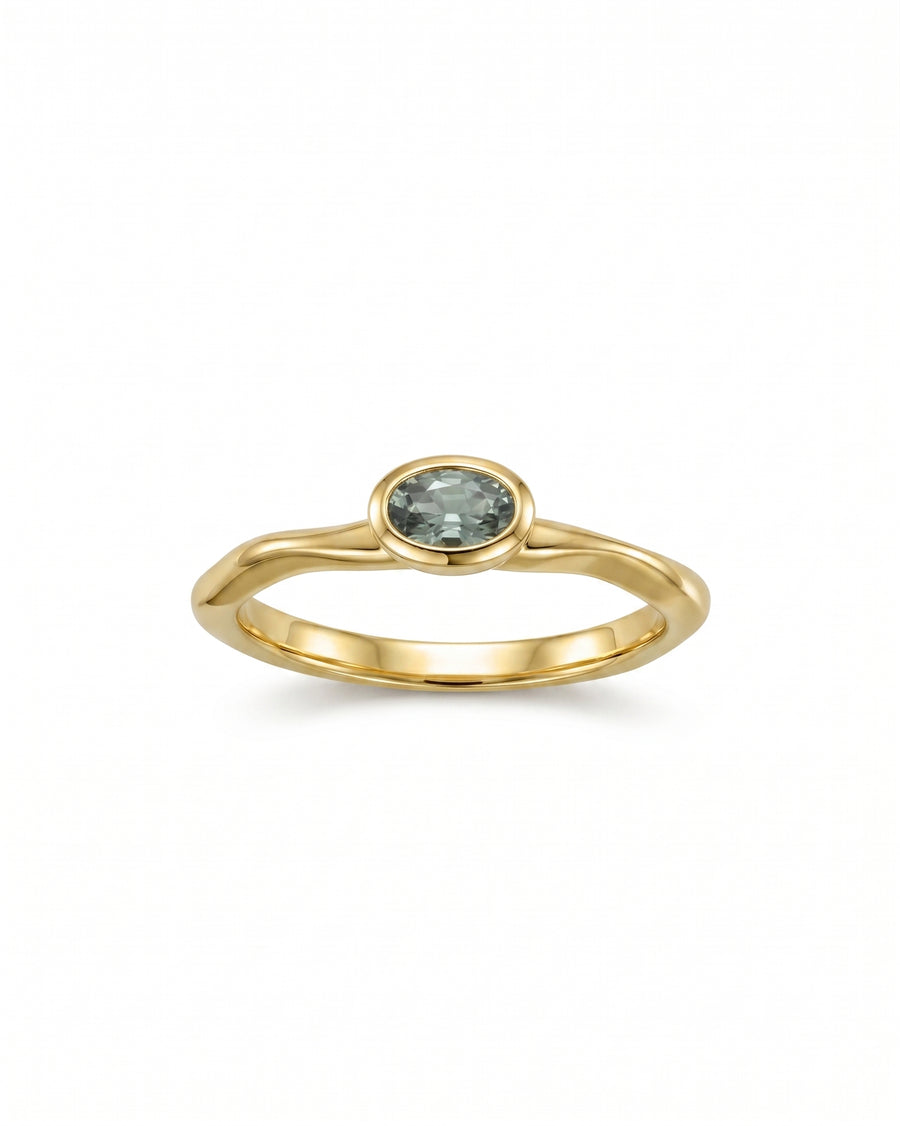 Gold ring with an oval blue sapphire in a bezel setting.