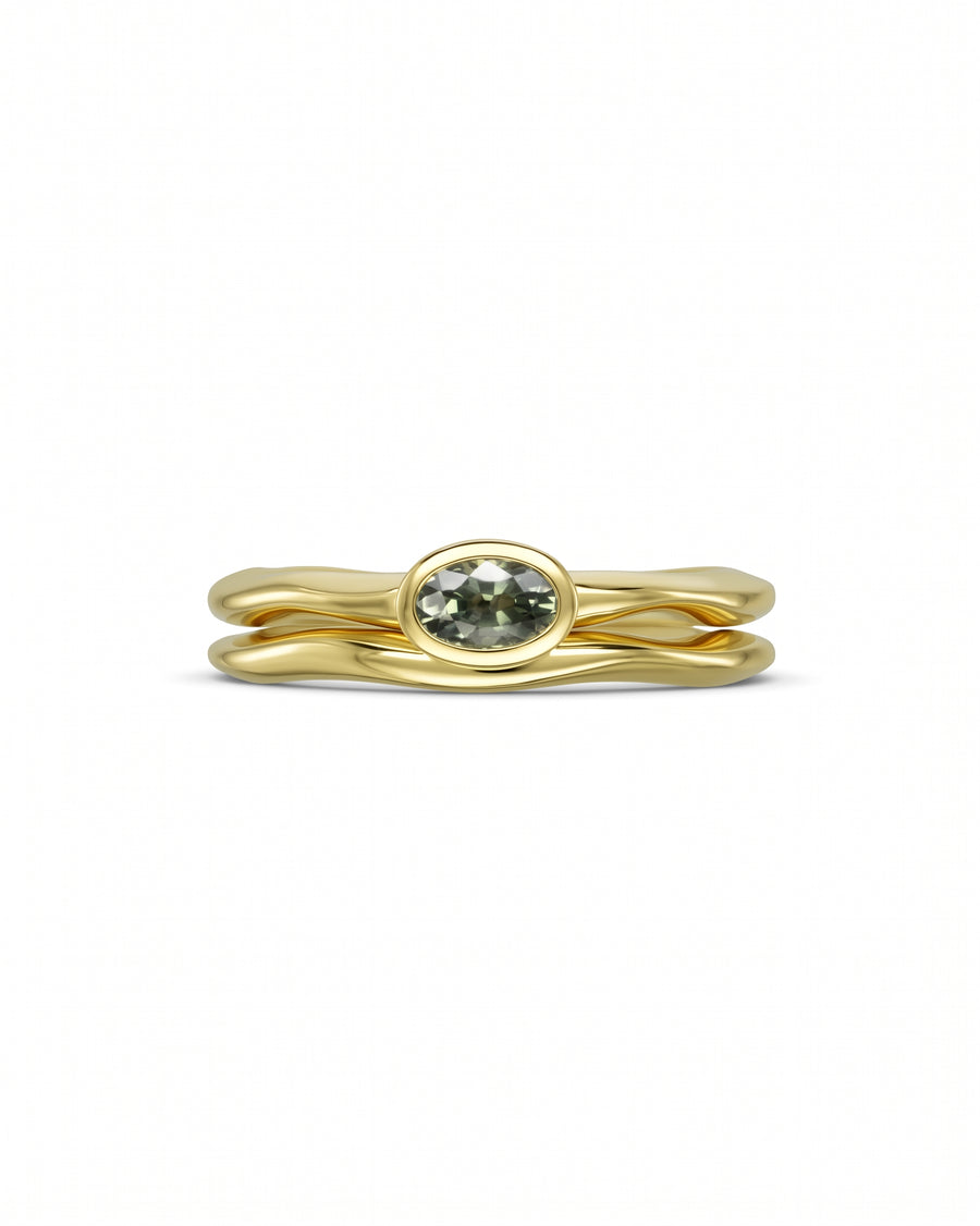 Gold ring set with an oval green sapphire.