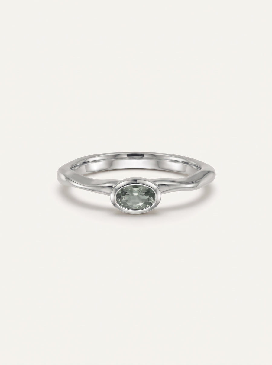 Platinum engagement ring featuring an oval-cut green sapphire in a bezel setting on a smooth, wavy band.