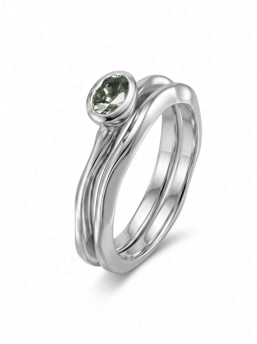 Oval green sapphire set in a polished silver bezel on a wavy, organic-style band.