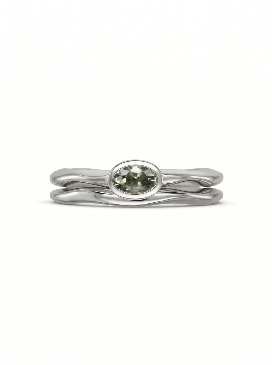 Silver stackable ring set featuring an oval-cut green sapphire in a smooth bezel setting with wavy bands.