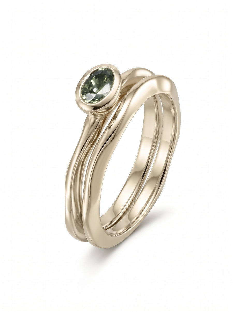 Oval green sapphire bezel-set in a gold band, paired with a matching wavy gold stacking ring.