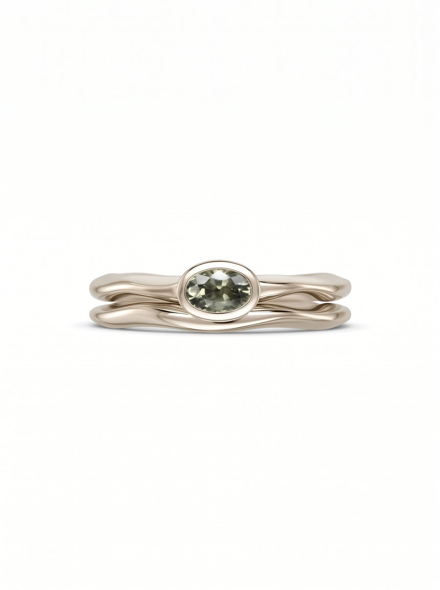 Oval green sapphire engagement ring set in a wavy, polished gold band.