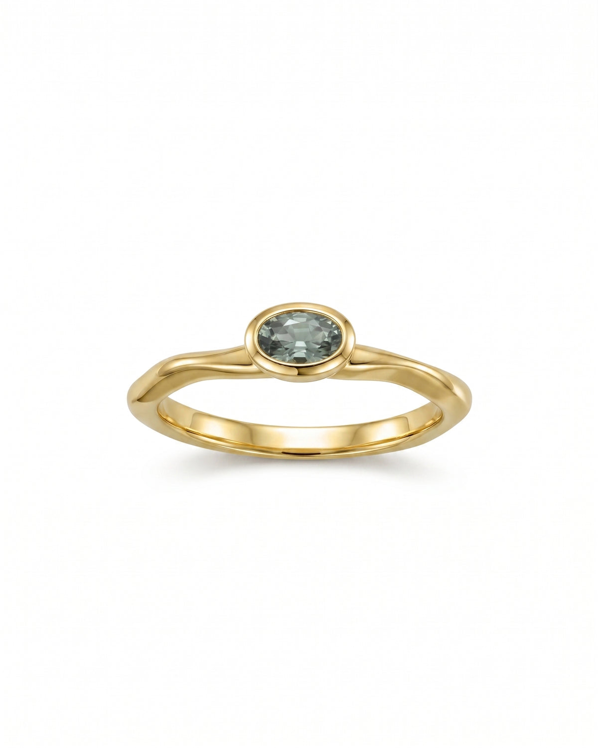 Oval green sapphire bezel-set in a polished yellow gold band with a wavy, organic design.