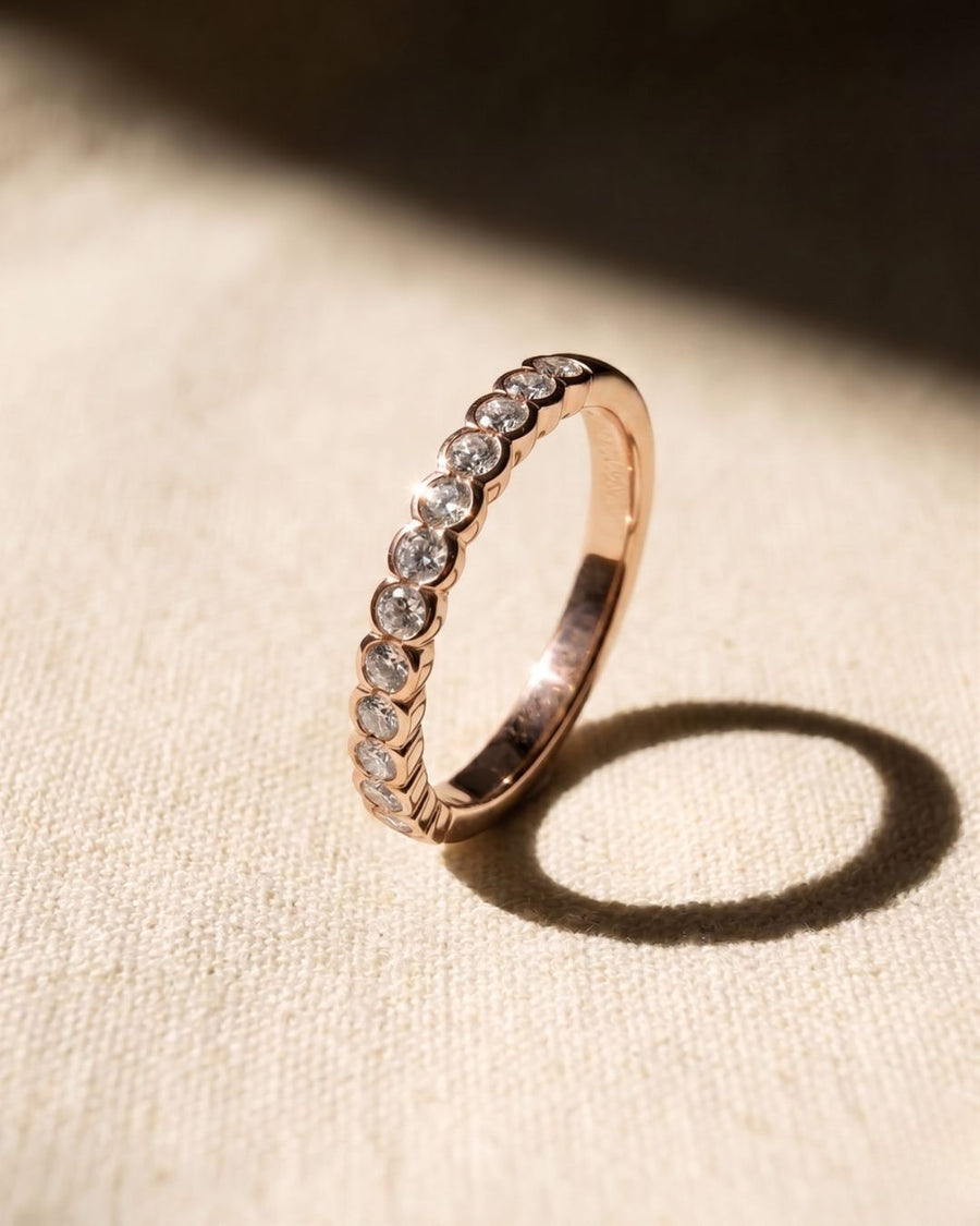 Rose gold ring with a scalloped edge and round diamonds.
